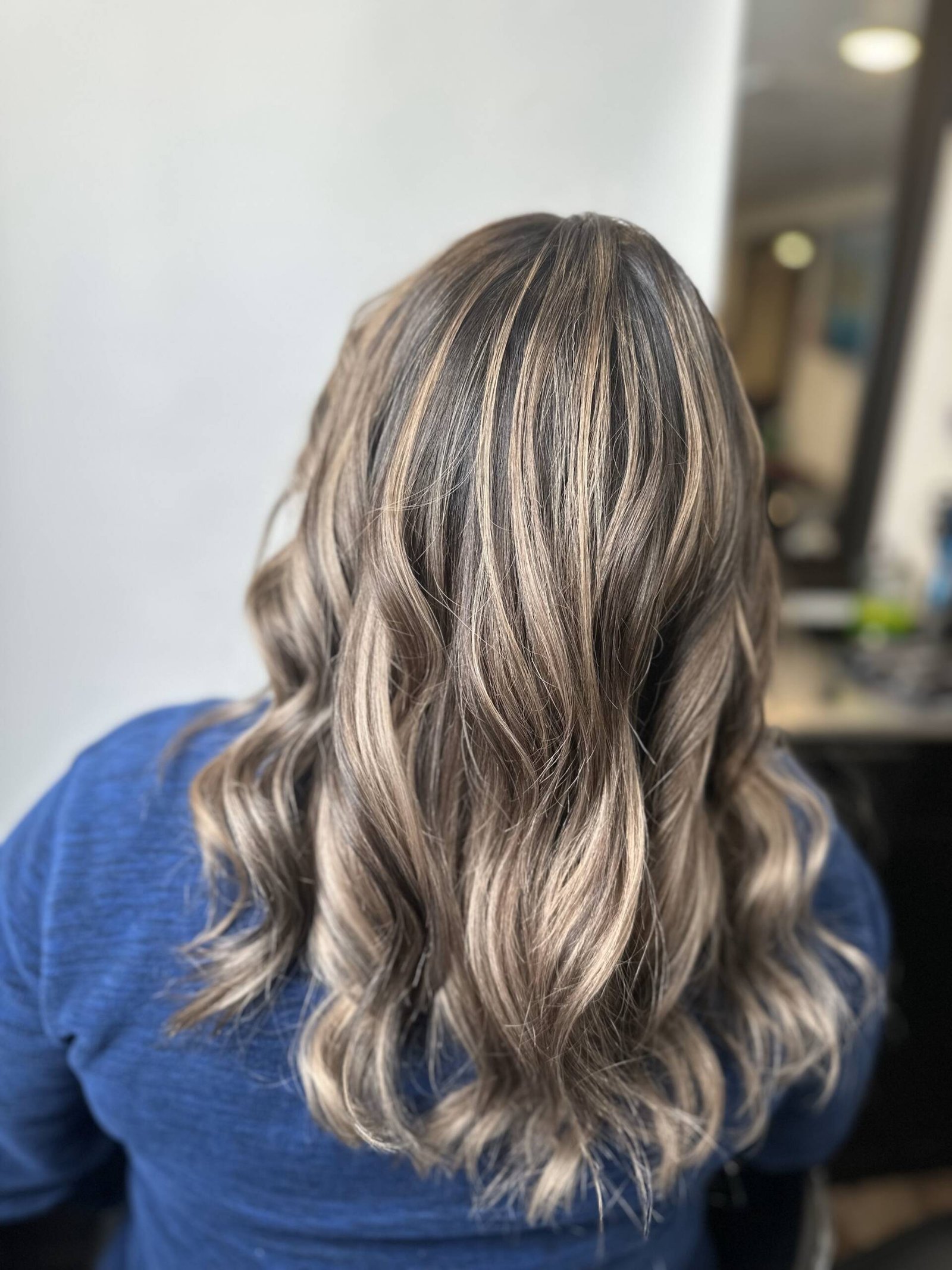 Close-up of woman's hair with caramel and honey blonde highlights catching the sunlight, creating a shimmering effect.