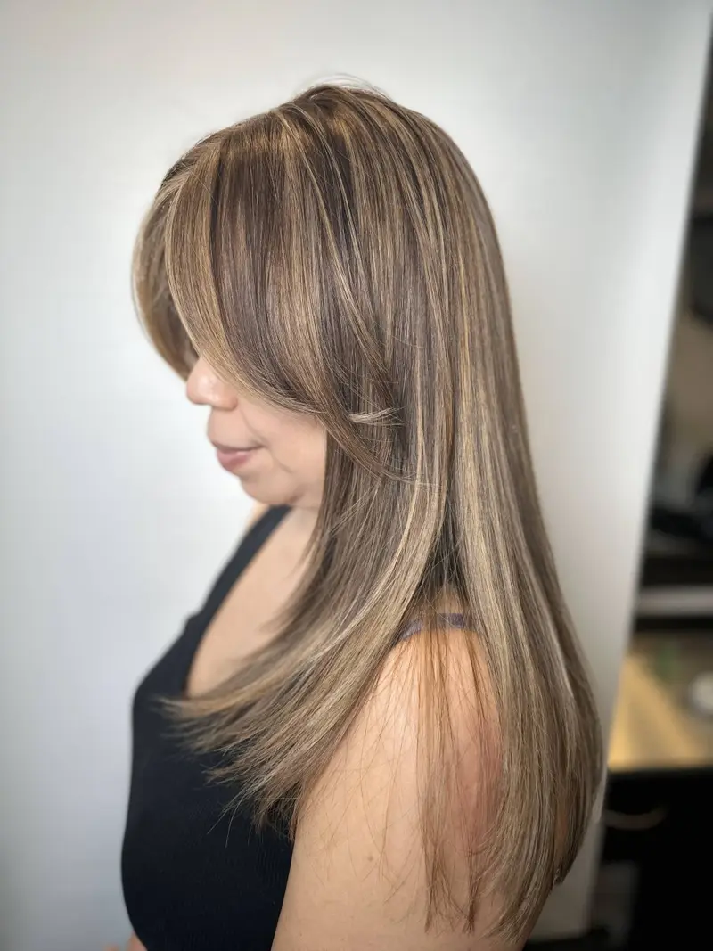 A woman with ash brown hair and subtle blonde highlights flowing elegantly.